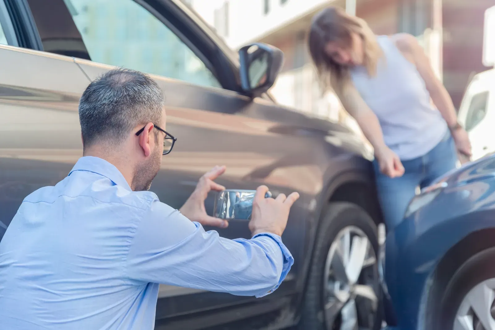 Driver photographing vehicle damage after an incident