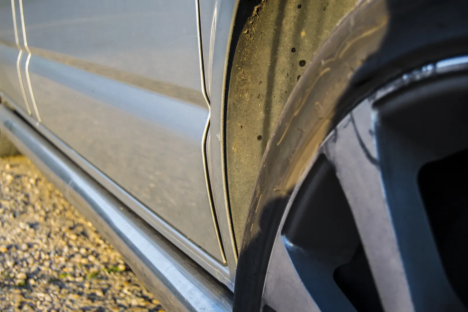 Scuffed alloy wheel and lower body panel of a silver car