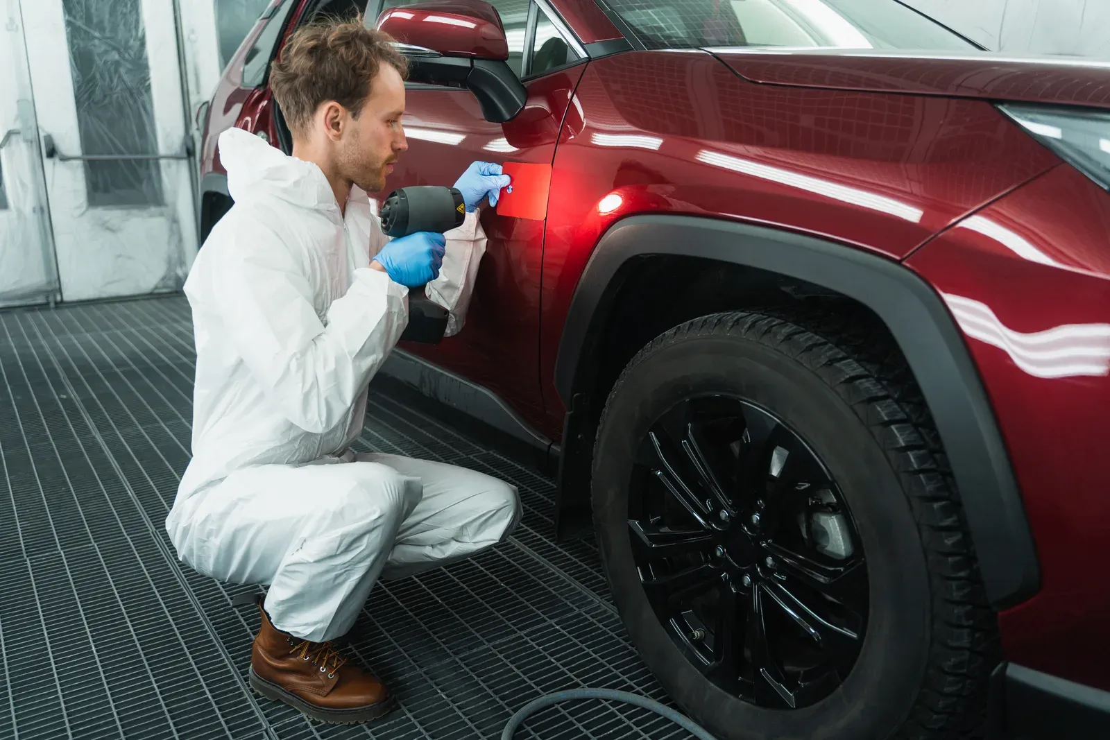 Technician checking a mixed paint color against a vehicle panel at Prime Auto Body