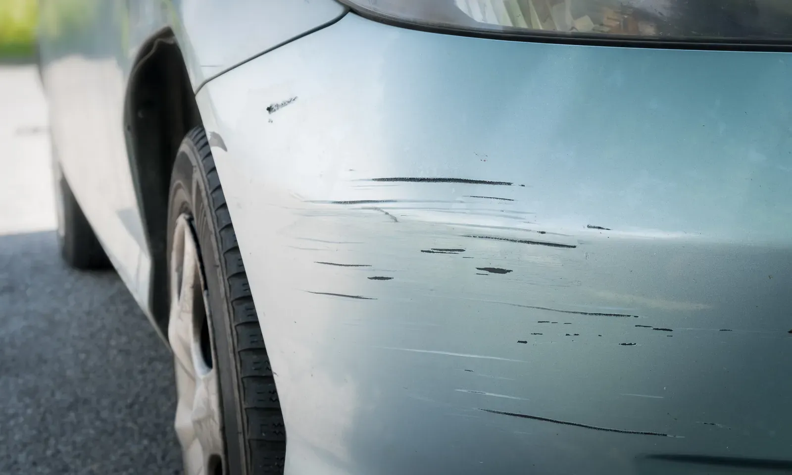 Close-up of a scratch cutting through the clear coat on a car body panel