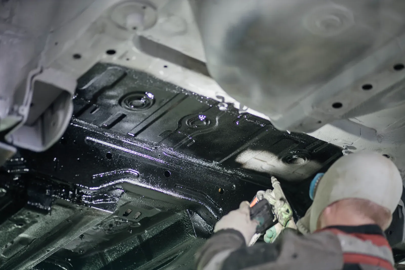 Underside of a car on a hoist during an inspection and protective coating treatment