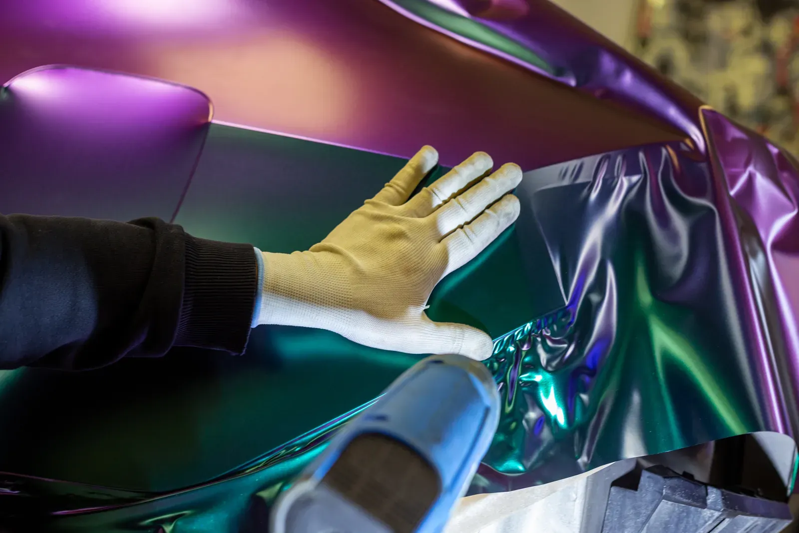 Installer applying vinyl film to a vehicle panel after body and paint repair was completed